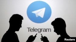 In this file photo, two men pose with smartphones in front of a screen showing the Telegram logo in this picture illustration taken in Zenica, Bosnia and Herzegovina, Nov. 18, 2015.