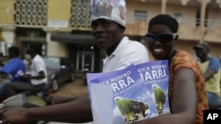 Supporters of presidential candidate Cheick Modibo Diarra distribute campaign flyers from the back of a moped as they ride in a campaign caravan through the streets of Bamako, Mali, July 20, 2013.