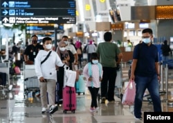 Orang-orang berjalan dengan barang bawaan mereka di Bandara Soekarno-Hatta untuk kembali ke kampung halaman atau "mudik." (Foto: Reuters)