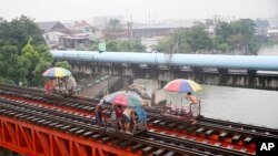Warga naik "trolley", kereta yang dibuat oleh penduduk setempat sebagai alat transportasi dengan memanfaatkan jalur kereta api saat topan yang memicu hujan mulai mengguyur kota Manila, Filipina (17/10). 