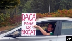 Seorang perempuan menunjukkan sebuah poster sembari berkendara melalui kemacetan di Portland, Oregon, 5 September 2017. 