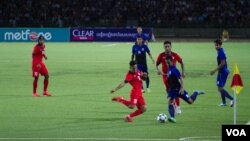 រូបឯកសារ៖ កីឡាករ​បាល់​ទាត់​ជម្រើស​ជាតិ​កម្ពុជា​ ក្នុង​ការប្រកួត​ជាមួយ​ក្រុម​សឹង្ហបុរី ក្នុង​ការប្រកួត​ជំរុះ​វគ្គ​បឋម​អាស៊ី​ ដើម្បី​ឈាន​ទៅ​កាន់​ការប្រកួត​ពាន​រង្វាន់​ពិភពលោក​ នៅ​ពហុកីឡាដ្ឋាន​ជាតិ​អូឡាំពិក​ កាល​ពី​ថ្ងៃ​ទី១១​ ខែ​មិថុនា ឆ្នាំ​២០១៥។ ​ (នូវ​ ពៅ​លក្ខិណា/VOA)