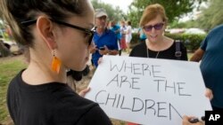 Susan Snyder, right, helps Anabelle Andon, left, make signs before a demonstration in front of the Immigration and Customs Enforcement offices, June 1, 2018, in Miramar, Fla. 