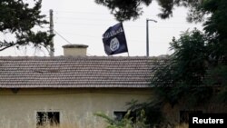 Bendera ISIS terlihat di atas kantor bea cukai di perbatasan di Jarablus, Suriah, terlihat dari Karkamis, di provinsi Gaziantep, Turki (1/8).