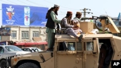 Taliban fighters, standing on a Humvee, guard in front of Hamid Karzai International Airport, in Kabul, Afghanistan, Aug. 16, 2021. 