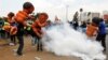 Protesters carrying giant baby models run away after riot police fired tear gas to disperse them during a march dubbed "Kenya ni Kwetu" in Kenya's capital Nairobi, Feb. 13, 2014. 