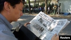 FILE - A Chinese visa applicant reads a Beijing newspaper as he waits outside the U.S. Embassy.