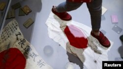 资料照：在北京的中国人民抗日战争博物馆内，一名参观者走在玻璃地板下展示的二战期间缴获的日本旗帜。（2015年9月1日）