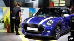 Cleaners wait near a MINI Cooper Cabrio displayed at the China Auto Show in Beijing, China, April 26, 2018.