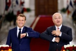 French President Emmanuel Macron and Iraq's President Barham Salih greet each other with an elbow bump as they attend a news conference in Baghdad, Iraq, Sept. 2, 2020.