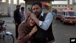 A man comforts a Christian woman who lost her husband in a deadly shooting incident, outside a hospital in Quetta, Pakistan, April 15, 2018.