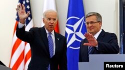 U.S. Vice President Joe Biden (L) waves as he meets Polish President Bronislaw Komorowski in Warsaw, March 18, 2014.