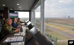 Presiden Rusia Vladimir Putin, tengah, Menteri Pertahanan Rusia Sergei Shoigu, kiri, dan Staf Umum Rusia Valery Gerasimov, kanan, menyaksikan latihan strategis bersama angkatan bersenjata Federasi Rusia dan Republik Belarus Zapad-2021 di tempat latihan Mulino di wilayah Nizhny Novgorod, Rusia, Senin, 13 September 2021. (Foto: via AP)