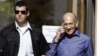 Former Israeli Prime Minister Ehud Olmert (R) speaks on the phone as he leaves the Jerusalem District court, September 24, 2012.