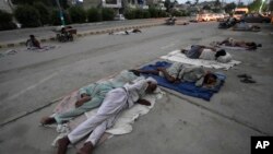 Para buruh tidur di pinggir jalan pada pagi hari musim panas yang terik di Karachi, Pakistan (29/5). Gelombang udara panas sedang melanda India dan Pakistan. 