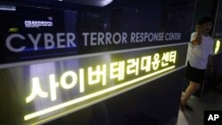 FILE - A woman walks by a sign at Cyber Terror Response Center of National Police Agency in Seoul, South Korea. 