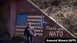 KOSOVO -- A man walks past graffiti reading 'Thank You NATO' and featuring the U.S. flag near the village of Stagovo, March 24, 2019