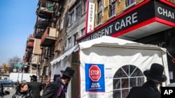 布鲁克林一家急诊室的帐篷，招牌上告诉怀疑自己感染冠状病毒的人到里面等候检测。（美联社）