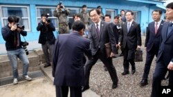 South Korean Unification Minister Cho Myoung-gyon, center, shakes hands with a North Korean official as he crosses to North Korea for the meeting at the northern side of the Panmunjom in North Korea, Thursday, March 29, 2018. (Korea Pool via AP)