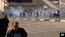 Para pengunjuk rasa berusaha menghindari gas air mata yang ditembakkan pasukan keamanan, selama unjuk rasa dari para pengikut imam Syiah yang berpengaruh di Irak, Muqtada al-Sadr (11/2). Baghdad, Irak. (foto: AP Photo/Karim Kadim)
