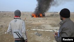 Sunni Muslim fighters watch as a police vehicle burns during clashes in Ramadi, Iraq, Jan. 2, 2014.