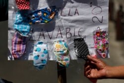 FILE - A customer picks out a fabric face mask being sold on a street in Mexico City, March 23, 2020.