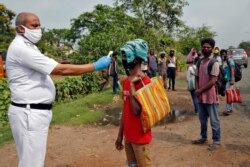 A police officer takes the temperature of a migrant worker at a check point on their way home, during an extended COVID-19 lockdown on the outskirts of Kolkata, India, May 5, 2020.