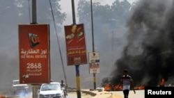 Les automobilistes passent devant des pneus en feu utilisés comme barricade alors que les manifestants se rassemblent pour faire pression sur le gouvernement à Khartoum, au Soudan, le 21 octobre 2020. REUTERS/Mohamed Nureldin Abdallah