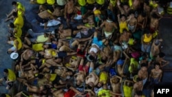 FILE - A photo taken on March 27, 2020, shows prison inmates, some resting, others gesturing, in cramped conditions in the crowded courtyard of the Quezon City jail in Manila, Philippines.