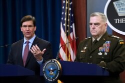 FILE - Defense Secretary Mark Esper, left, standing with Joint Chiefs​ Chairman Gen. Mark Milley, right, speaks during a news conference at the Pentagon in Washington, Dec. 20, 2019.