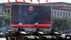 FILE - Chinese President Xi Jinping is displayed on a screen as Type 99A2 Chinese battle tanks take part in a parade commemorating the 70th anniversary of Japan's surrender during World War II, Tiananmen Gate, Beijing, China. 