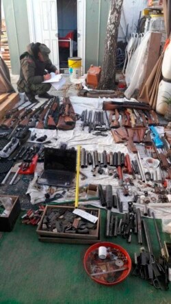 In this photo provided by the Argentine Ministry of Security, a police officer takes inventory a cachet of weapons seized by authorities at an undisclosed location in Argentina, June 26, 2019.