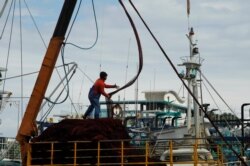 FILE - A fisherman reels in nets in a fishing marina shared with the naval base harbor in Suao, Taiwan, Dec. 5, 2012.