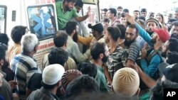 A crowd gathers around an ambulance carrying victims killed in a bus accident near Kishtwar, about 217 kilometers (135 miles) southeast of Srinagar, Indian-controlled portion of Kashmir, Sept. 14, 2018.