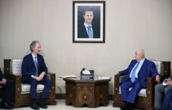 In this photo released by the Syrian official news agency SANA, the U.N.'s special envoy for Syria Geir Pedersen, left, meets with Syrian Foreign Minister Walid al-Moallem, in Damascus, Syria, Sept. 23, 2019.