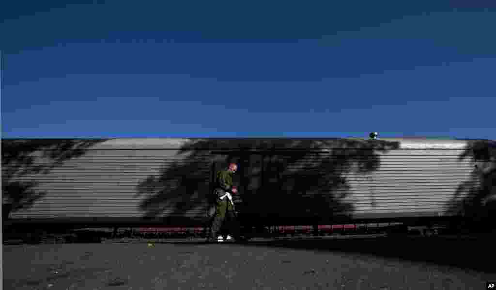 An armed pro-Russian rebel patrols the area next to a refrigerated train loaded with the bodies of victims, in Torez, eastern Ukraine, July 21, 2014.