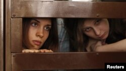 FILE - Nadezhda Tolokonnikova (L) and Maria Alyokhina, members of female punk band "Pussy Riot", look out from the defendent's cell in a courtroom in Moscow, July 30, 2012. 