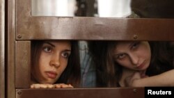 Nadezhda Tolokonnikova (L) and Maria Alyokhina, members of female punk band "Pussy Riot", look out from the defendent's cell in a courtroom in Moscow July 30, 2012. 