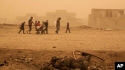 Un groupe de civils passe près du corps d'un militant de l'État islamique en fuite sous des bombardements intensifs de l'EI dans plusieurs zones sous le contrôle de l'armée irakienne, Mossoul, Irak, 2 décembre 2016.