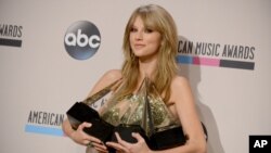 Taylor Swift berpose di belakang panggung dengan empat penghargaan yang diraihnya pada American Music Awards (24/11). (AP/Invision/Jordan Strauss)