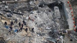 FILE - In this June 26, 2021 photo, rescue workers search in the rubble at the Champlain Towers South Condo, in Surfside, Fla.