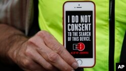 FILE - A man holds up his iPhone during a rally in support of data privacy in San Francisco, Feb. 23, 2016. 