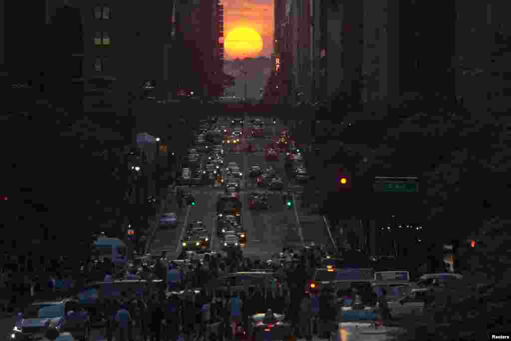 Orang-orang mengambil gambar matahari terbenam di jalan 42 kota New York, saat terjadinya&nbsp; &quot;Manhattanhenge&quot; yang berlangsung setiap dua tahun, 29 Mei 2013. 