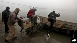 Tim vaksinasi di India mendorong sepeda bermuatan kotak-kotak vaksin ke dalam perahu untuk dibawa ke desa Kosi, 180 km dari Patna. Karena kotak standar styrofoam mudah rusak, WHO memperkirakan, separuh dari jumlah vaksin itu akan rusak dalam perjalanan. Namun, tim mahasiswa dari Universitas Negeri Oklahoma berharap, dengan menggunakan kotak yang bisa dilipat, vaksin yang peka terhadap suhu, akan aman (foto: dok).