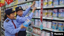FILE - Chinese commercial law enforcement personnel inspect milk powder products at a supermarket in Lianyungang, Jiangsu province, China.
