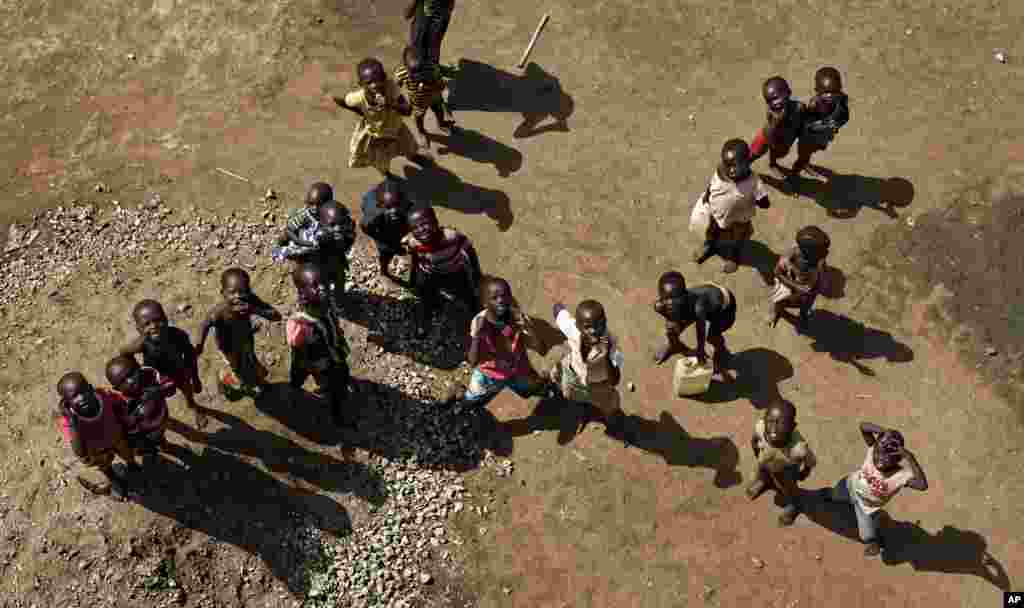 South Sudanese refugee children look up as a truck pumps water into a reservoir on top of a water tower, in a section of the sprawling complex of mud-brick houses and tents that makes up the Bidi Bidi refugee settlement in northern Uganda. Bidi Bidi is now the world&#39;s largest refugee settlement holding some of those who fled the civil war in South Sudan.