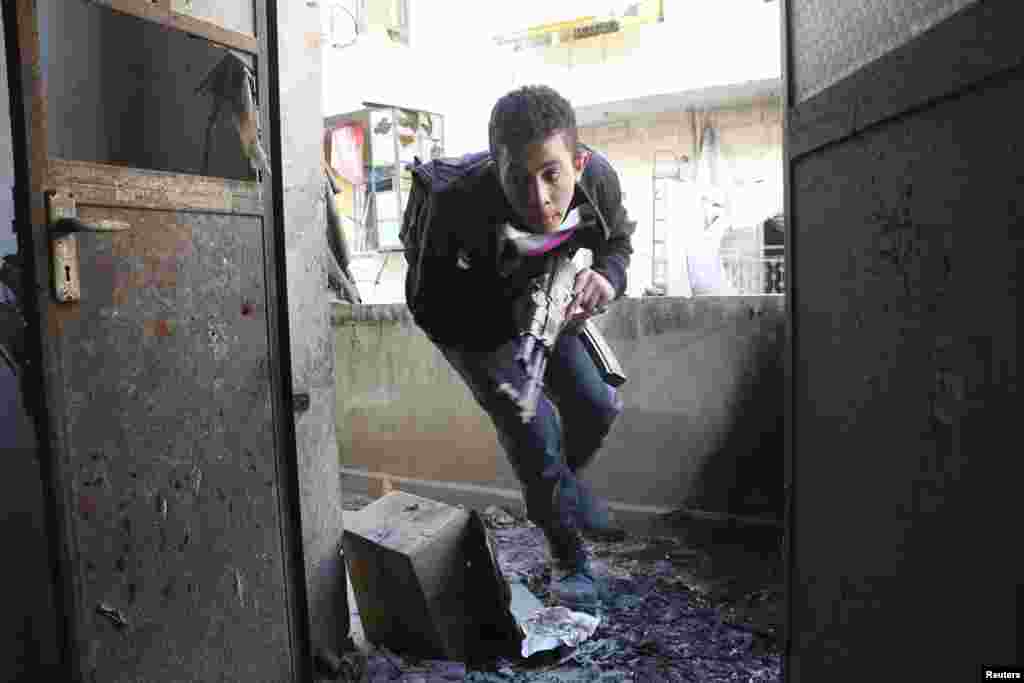A Free Syrian Army fighter runs for cover from forces loyal to President Bashar al-Assad in the Sheikh Maqsoud neighborhood of Aleppo, Feb. 16, 2014.&nbsp;