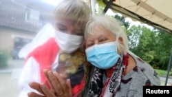 Lily Hendrickx, 83, a resident at Belgian nursing home "Le Jardin de Picardie" enjoys hugs and cuddles with Marie-Christine Desoer, the director of the residence, through a wall made with plastic sheets to protect against potential coronavirus disease.