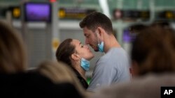 A couple kiss, at the Barcelona airport, Spain, Thursday, March 12, 2020. President Donald Trump, who had downplayed the coronavirus for weeks, suddenly struck a different tone, announcing strict rules on restricting travel from much of Europe to begin t