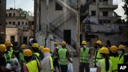 Volunteers from the American University of Beirut gather as they prepare to help remove debris in a neighborhood near the site of last week's explosion that hit the seaport of Beirut, Lebanon, Aug. 13, 2020. 